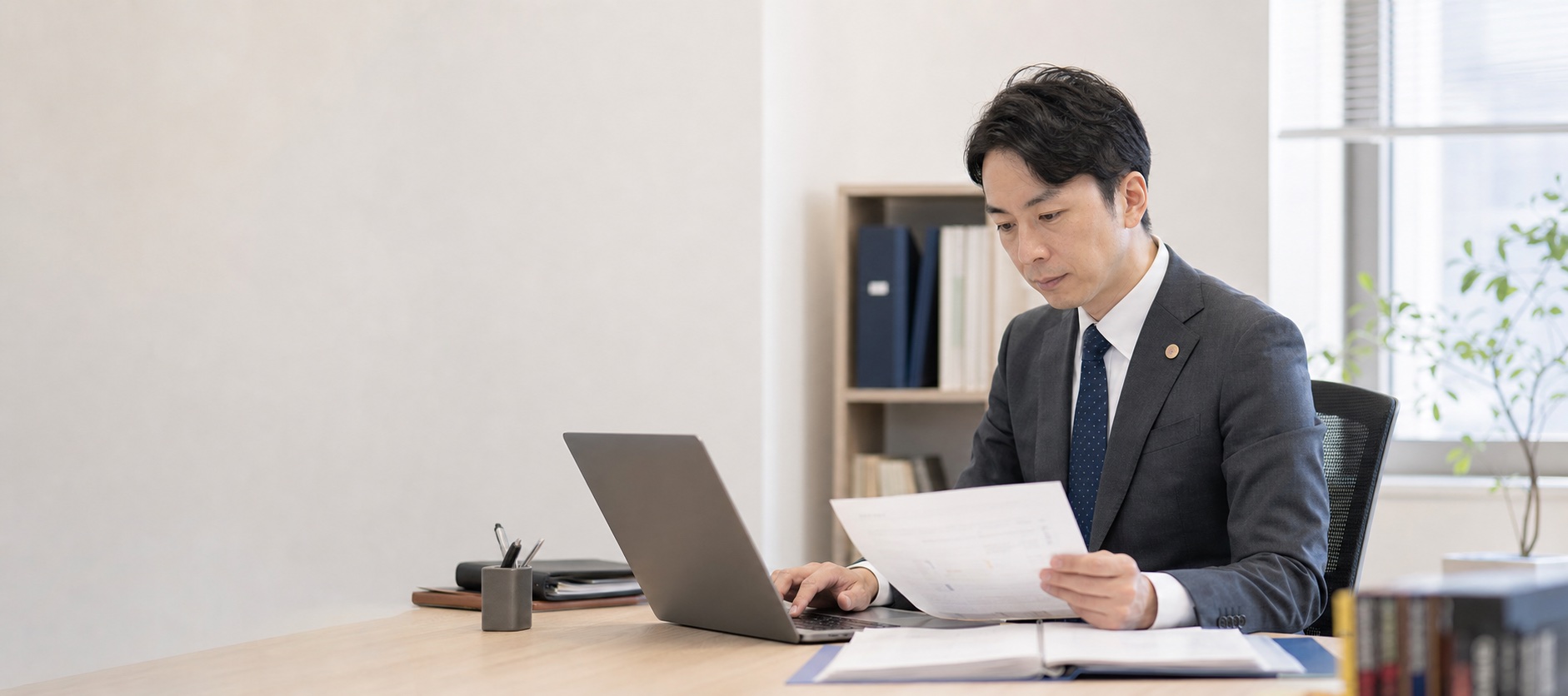 顧問先の書類とパソコンを照らし合わせる社労士